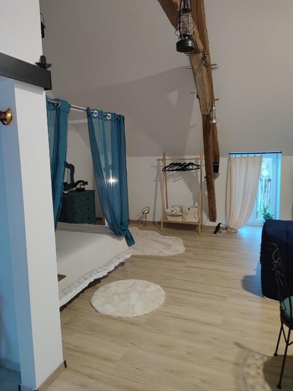 a room with a bed and blue curtains in it at Le nid du Berry in Célon