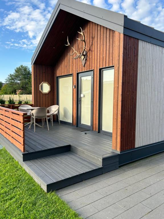 a house with a wooden deck with a table at Namelis Genio 7 in Palanga
