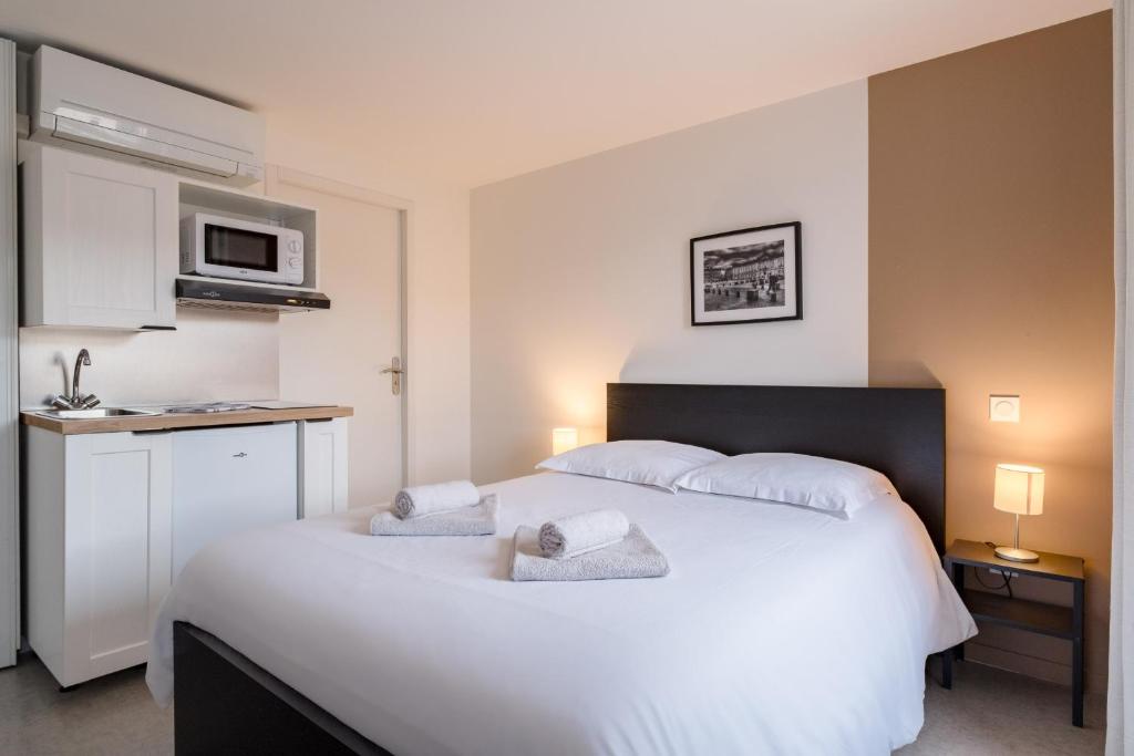 a bedroom with a white bed with towels on it at Solaria - Logement Climatisée à Jean Jaurès in Toulouse