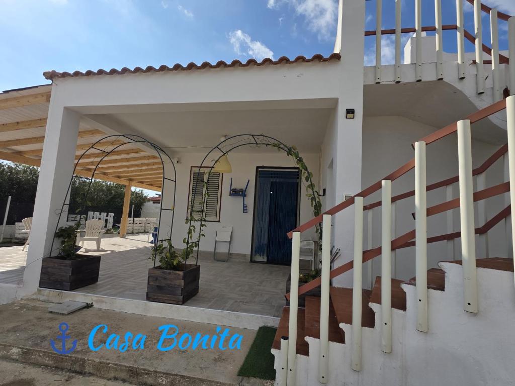 a white house with a staircase and a blue door at Casa Bonita Pachino in Pachino