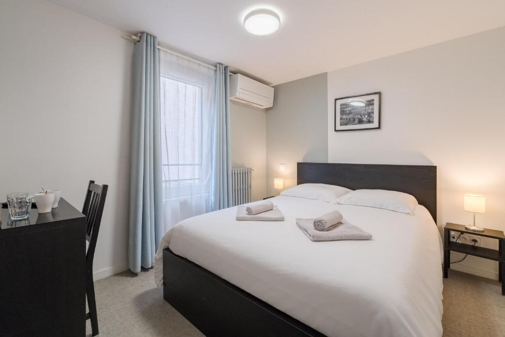 Un dormitorio con una gran cama blanca y una ventana. en Aube Cachée - Chambre Calme au Coeur de Toulouse, en Toulouse