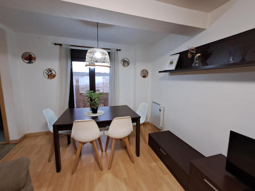a dining room with a black table and white chairs at Apartamento San Andrés in Teruel