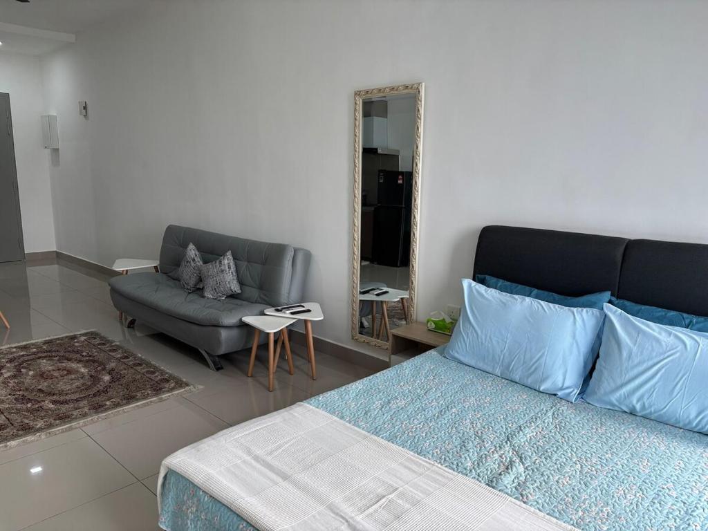 a bedroom with a bed and a couch and a mirror at HomeSweetHome Alinea Suites Shah Alam in Shah Alam