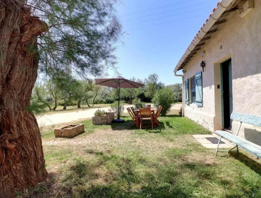 a patio with a table and an umbrella at Charmante maison en Camargue avec piscine partagée in Saintes-Maries-de-la-Mer
