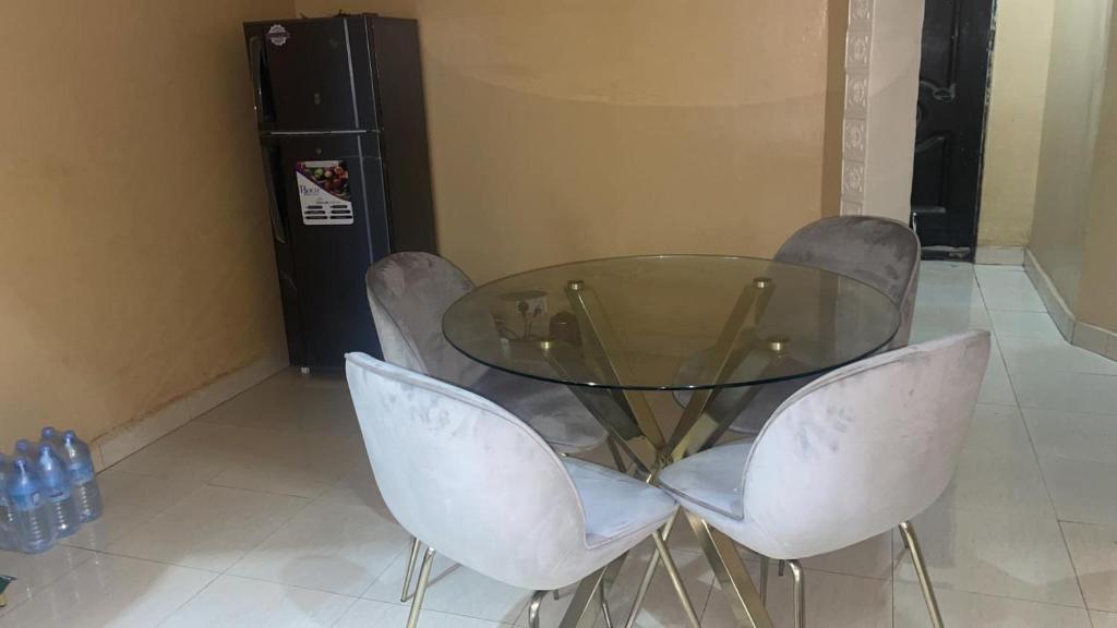 a glass table and two white chairs in a room at Marongs Appartment in Djalabango