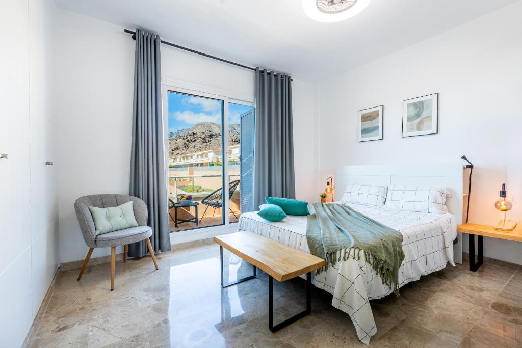 a bedroom with a bed and a table and a chair at Townhouse Playa Negra in Puerto de Santiago