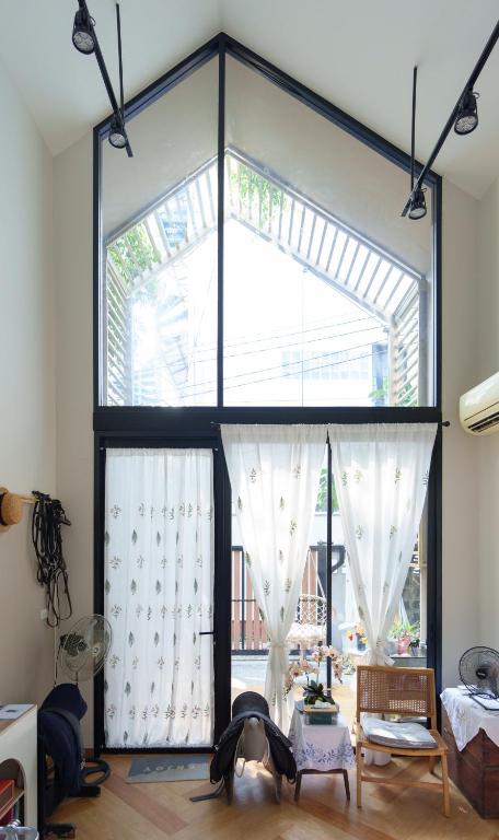 a room with a large window with white curtains at hiddenmoon cottage in Bangkok
