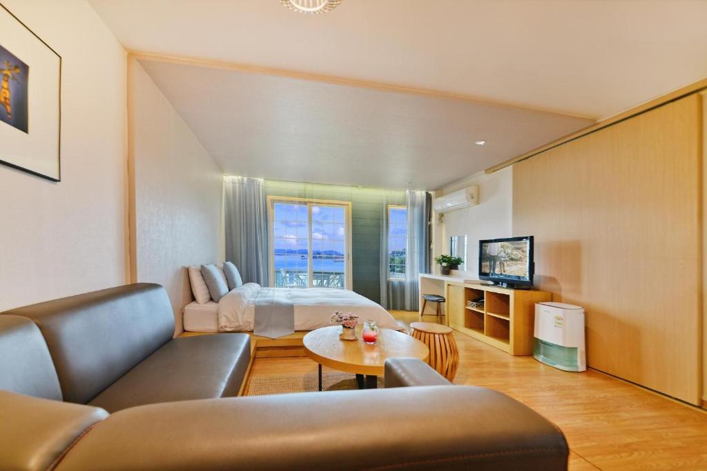 a living room with a bed and a couch and a table at Tongyoung Mongdolhouse Pension in Tongyeong