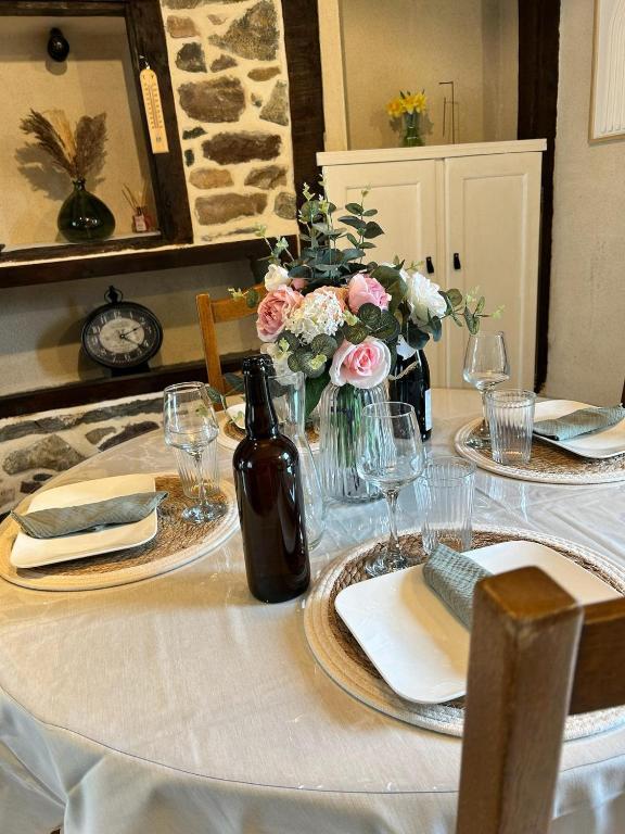 une table avec un chiffon de table blanc et des fleurs sur elle dans l'établissement La maison du malteur vue mer, à Plurien
