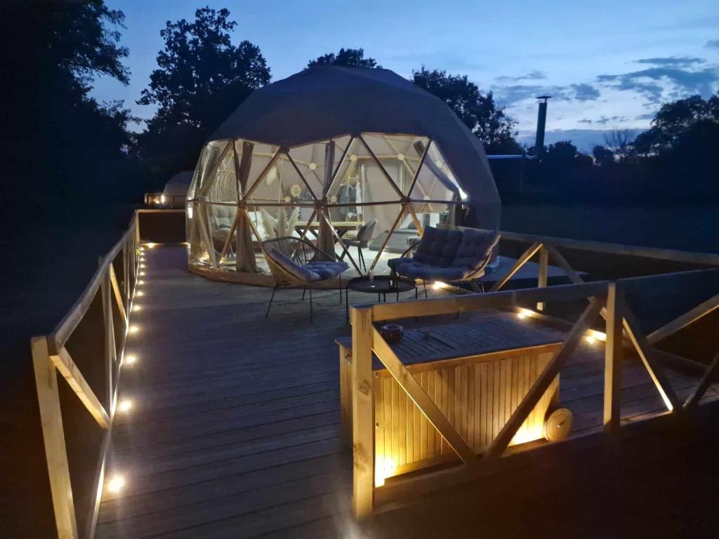 une tente en forme de dôme sur une terrasse la nuit éclairée dans l'établissement Grand dôme, à Biziat