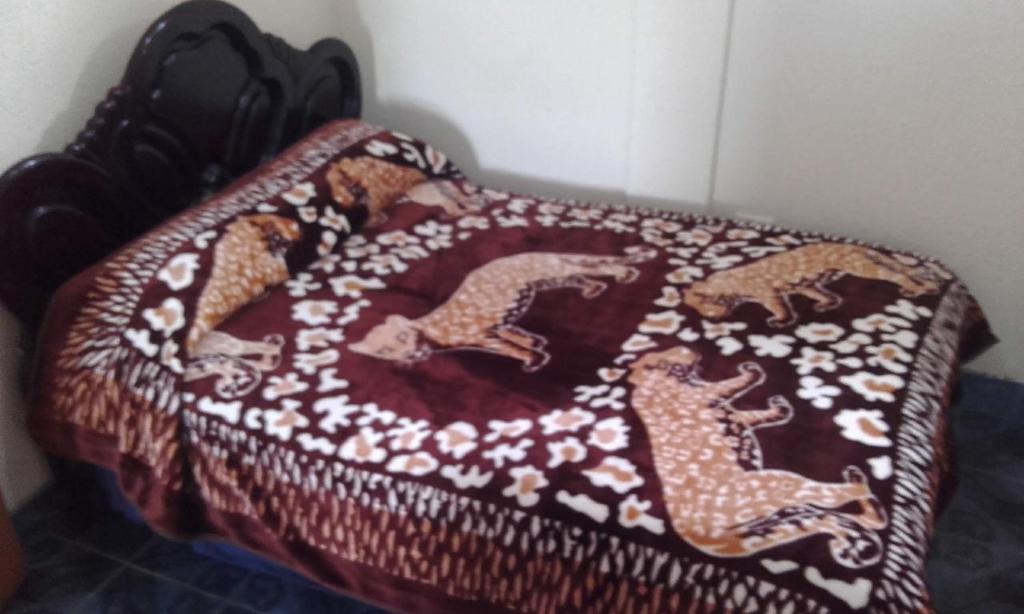 a bed with a blanket with horses on it at Hostal Lesly Salomé in Tulcán