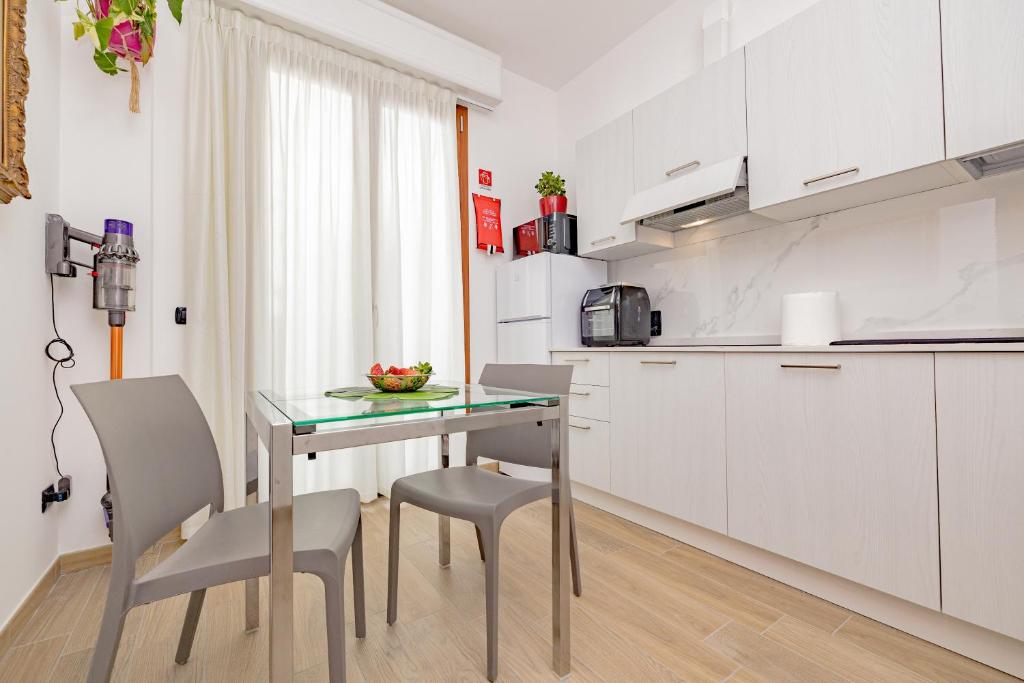a small kitchen with a glass table and chairs at A8 Aloe Rho Fiera -Monza Como-MXP AMPIO e LUMINOSO MONOLOCALE in Cesate