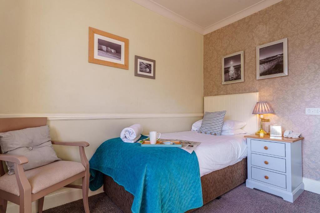 a small bedroom with a bed and a chair at Botany Bay Hotel in Broadstairs