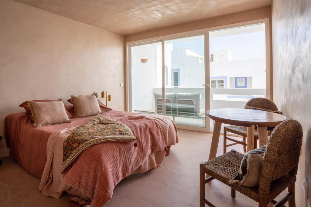 a bedroom with a bed and a table and a window at Formentera Especial in La Savina