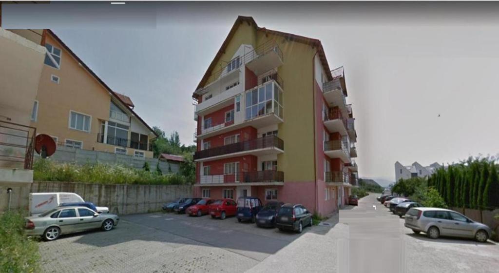 a building with cars parked in a parking lot at Apartament 3 camere 3 paturi pentru 6 pers,plus un pat de o persoană de rezervă in Sibiu