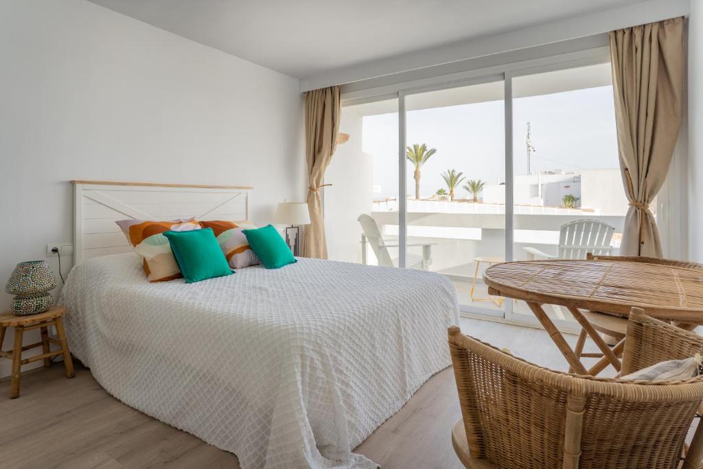 a bedroom with a bed with a table and a balcony at Formentera Especial in La Savina