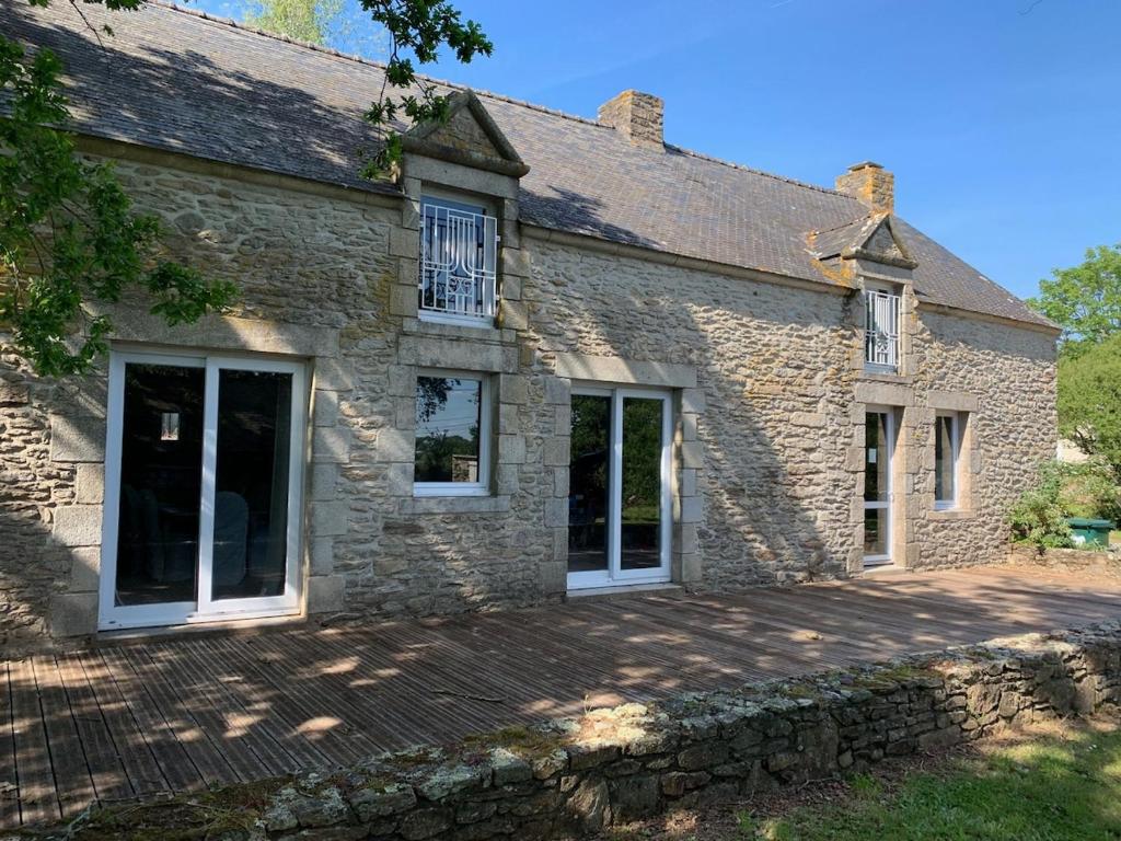 Elle offre une vue sur l'extérieur d'une maison en pierre dotée de grandes fenêtres. dans l'établissement FEREL Longère near beaches, 12 people, heated pool, à Férel