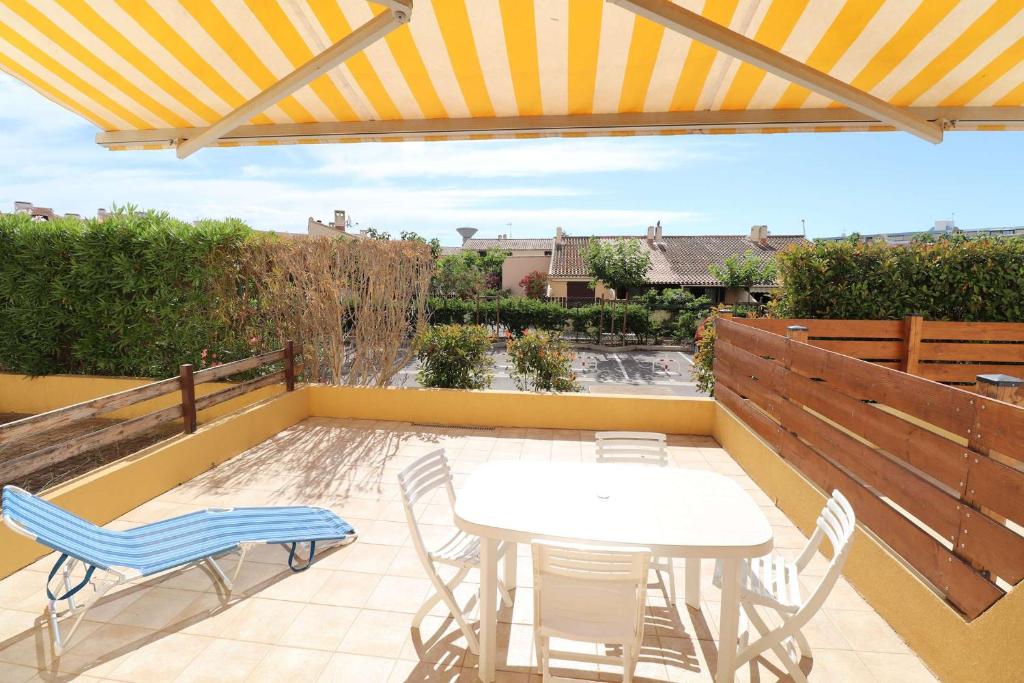 un patio avec une table et des chaises sur un toit dans l'établissement 2 pièces cabine grande terrasse RDC lave-linge parking 400m plage, au Grau-du-Roi