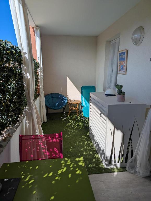 Cette chambre dispose d'un sol vert, d'une table et de chaises. dans l'établissement Appartement tout confort Résidence piscine 5 minutes de la plage Mèze, à Mèze