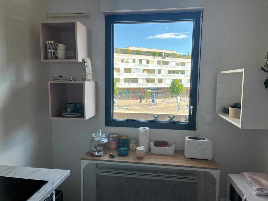 ein Fenster in einem Zimmer mit einem Tisch mit aounter sidx sidx sidx sidx in der Unterkunft Grand Studio avec Parking et Wifi in Castelnau-le-Lez