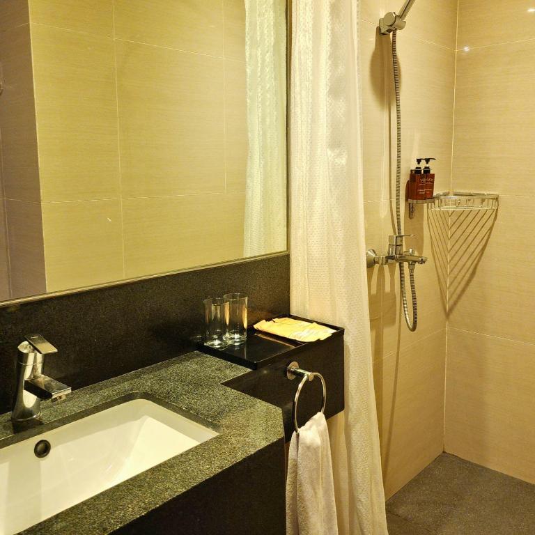 um banheiro com pia e chuveiro em Savoy Hotel Mactan em Mactan