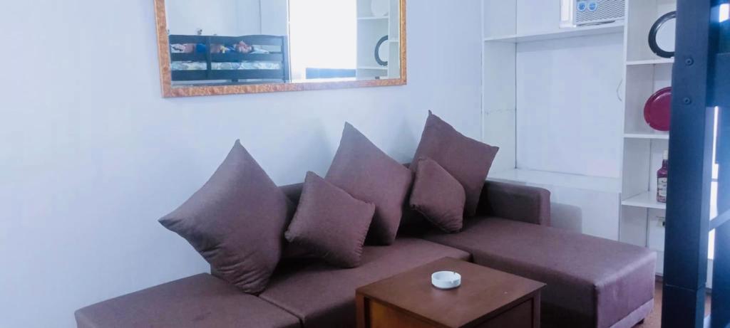 een woonkamer met een bank met kussens en een tafel bij Avida sm sucat condotel in Manilla