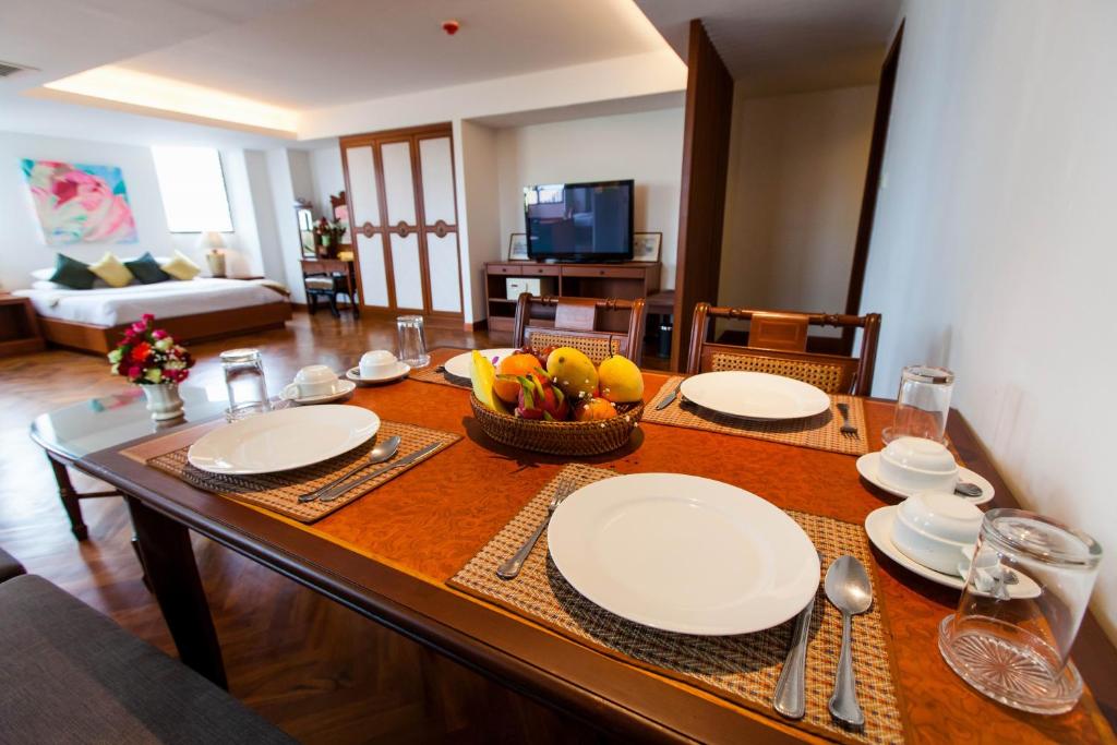 a dining room table with plates and fruit on it at The Grand Sathorn in Bangkok