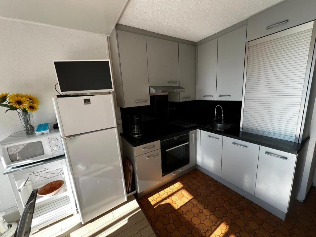 une cuisine avec des armoires blanches et un réfrigérateur blanc dans l'établissement Studio 5/6 Personnes avec Piscine et WIFI - FR-1-784-40, à Gruissan