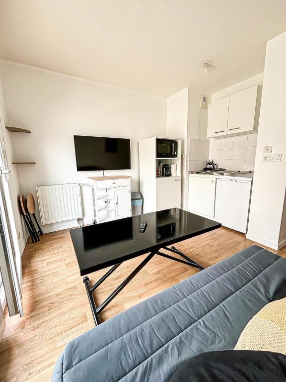 Il comprend un salon avec une table basse noire et une cuisine. dans l'établissement Studio tout équipé, fonctionnel avec parking privatif, à La Rochelle