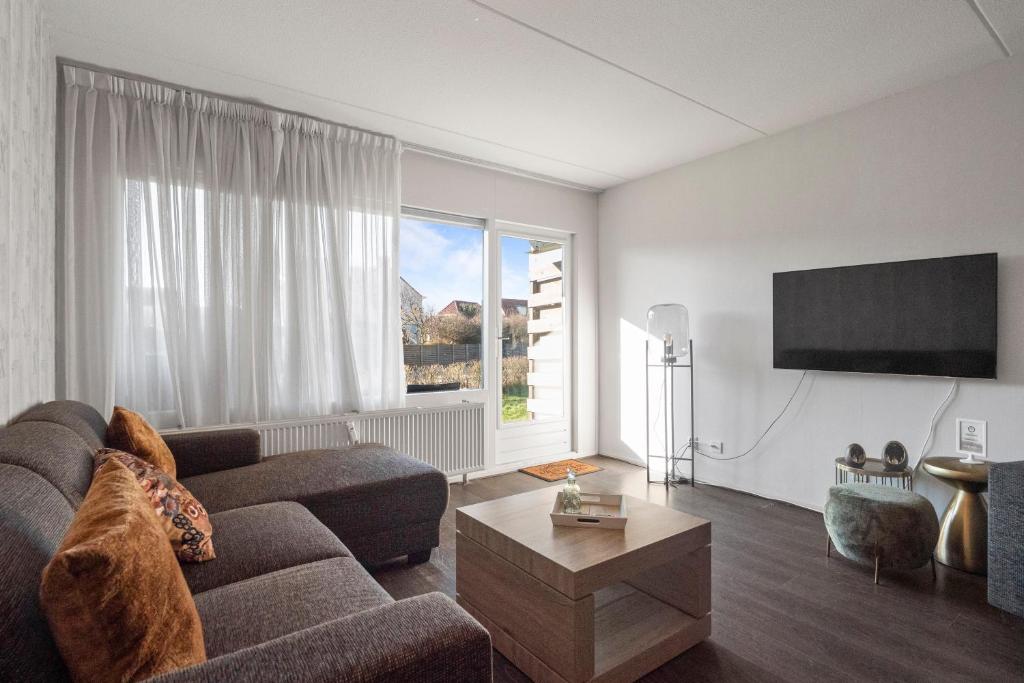a living room with a couch and a large window at Beach Appartement 14 - Aan de duinen, Callantsoog aan Zee in Callantsoog