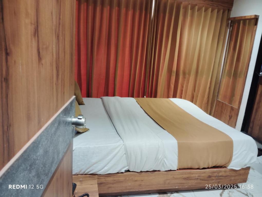 アーメダバードにあるHotel Peragon Innのベッドと赤いカーテンのある寝室