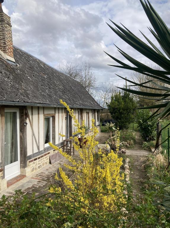 une maison avec des fleurs jaunes devant elle dans l'établissement Cottage normand de 1930, à Manneville-sur-Risle