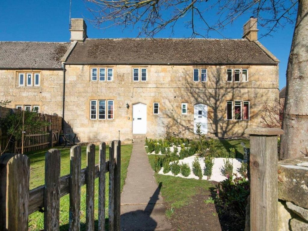 una vecchia casa in pietra con una recinzione in legno di Tiesel & Truffles Cottages a Cheltenham