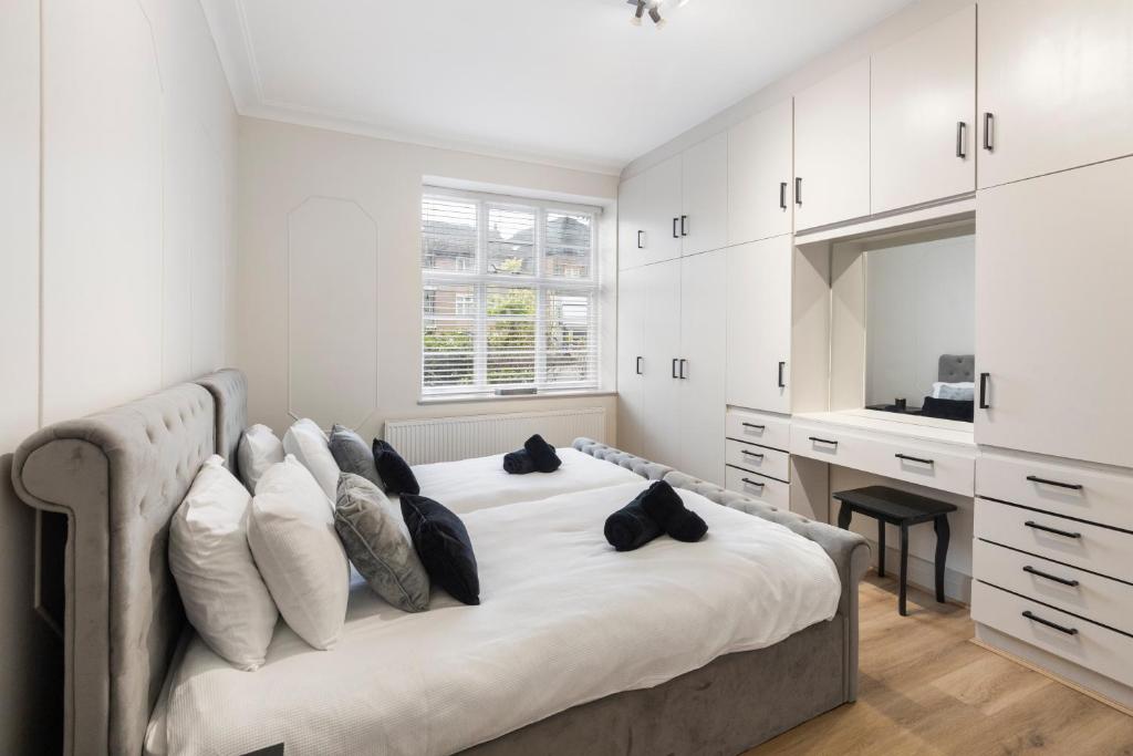 a white bedroom with a large bed with pillows at Cozy and spacious full size flat in London