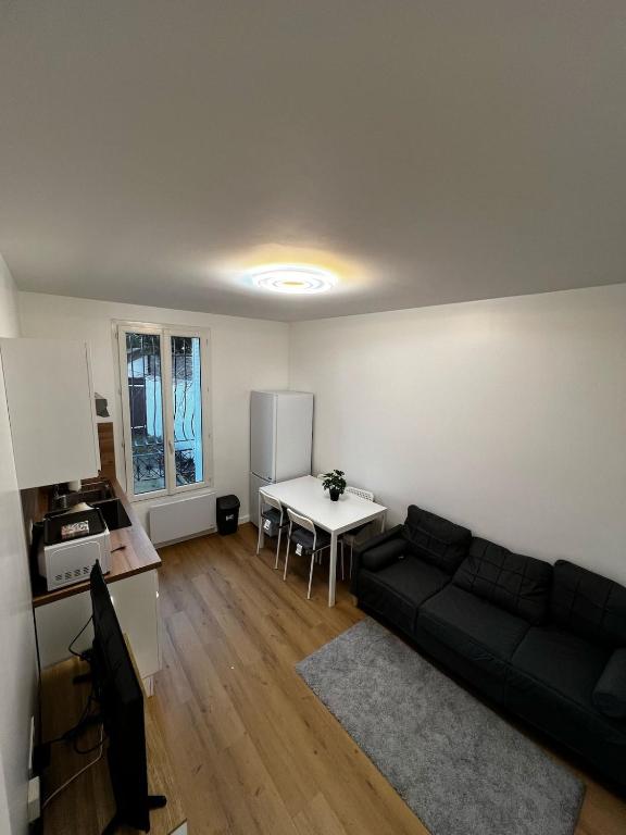 un salon avec un canapé noir et une table dans l'établissement 2-room apartment Argenteuil, à Argenteuil