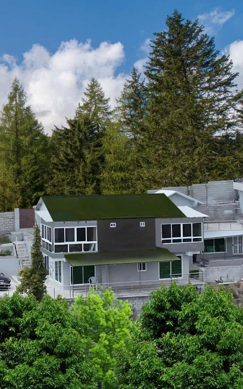 a large white building with a green roof at The Hermitage Cottage-Exclusive Mountain Escape in Murree
