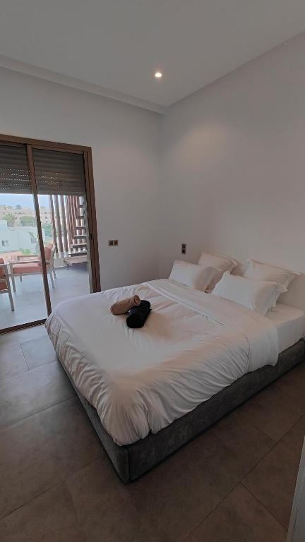 a large white bed with a black bag on it at Cocon moderne in Essaouira