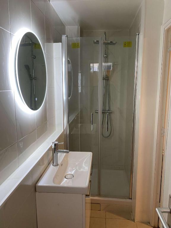 a bathroom with a sink and a shower with a mirror at Studio - à 1min du metro 8 mai 1945 - ligne 7 - 20 min d'Opéra Garnier in La Courneuve