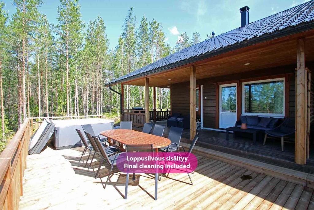 una cabina con terrazza in legno, tavolo e sedie di Villa Käpylinna B - 9 hlö, Himos Länsihuippu Ski-inout a Jämsä