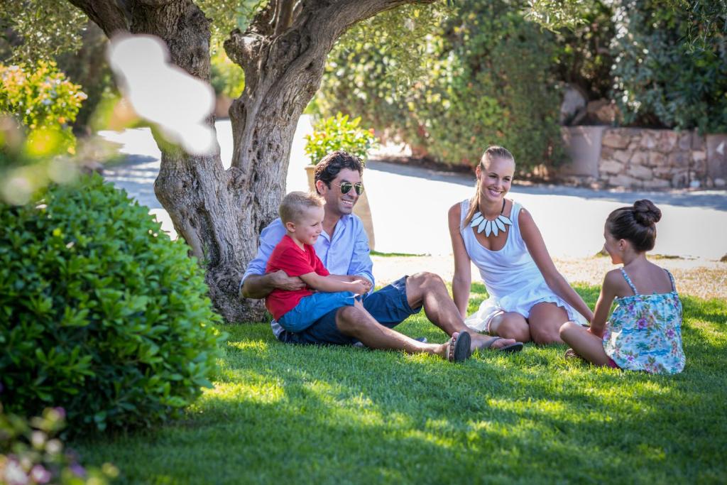 a group of people sitting in the grass at Chia Laguna - Hotel Village in Chia
