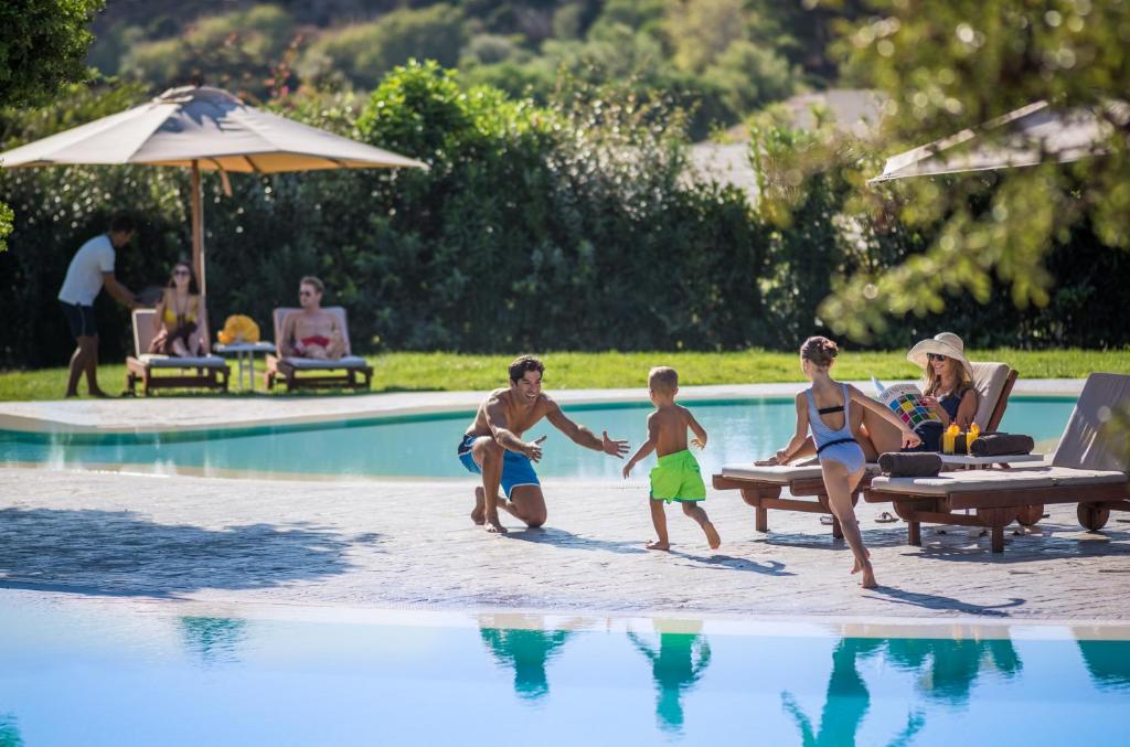 a group of people playing in a swimming pool at Chia Laguna - Hotel Village in Chia