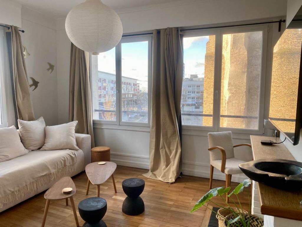 ein Wohnzimmer mit einer Couch und einigen Fenstern in der Unterkunft Appartement cosy en centre-ville in Calais