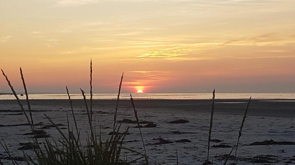 a sunset on the beach with the sun setting at Bønnerup Strand in Glesborg