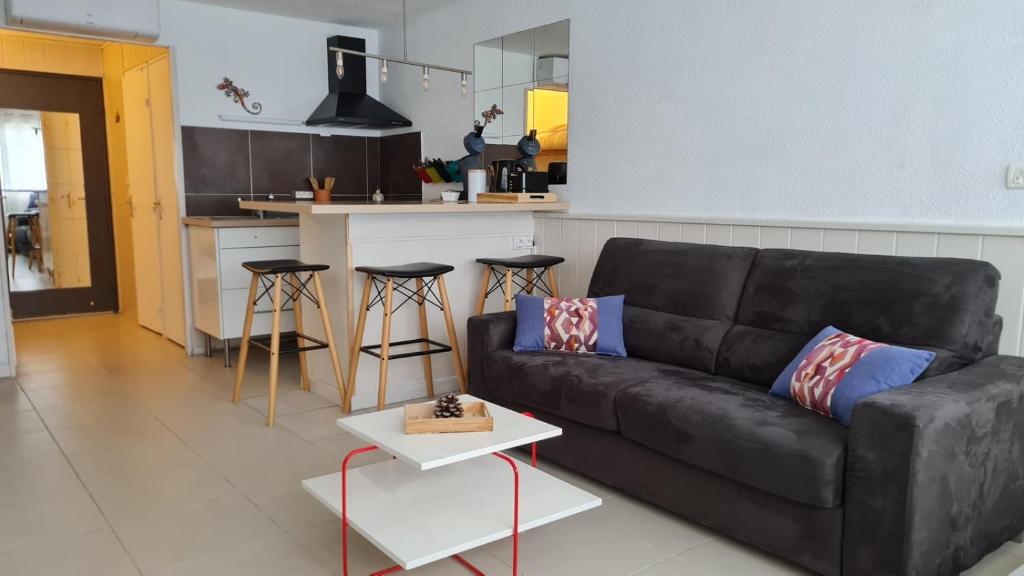 un salon avec un canapé noir et une cuisine dans l'établissement le 28 vue mer, au Grau-du-Roi