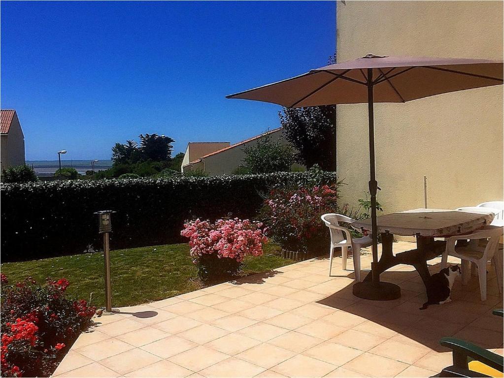 un patio avec une table et un parasol dans l'établissement VILLA 3 chbres Vue mer maison avec piscine ds residence proche commodites et plages de sable, à La Bernerie-en-Retz