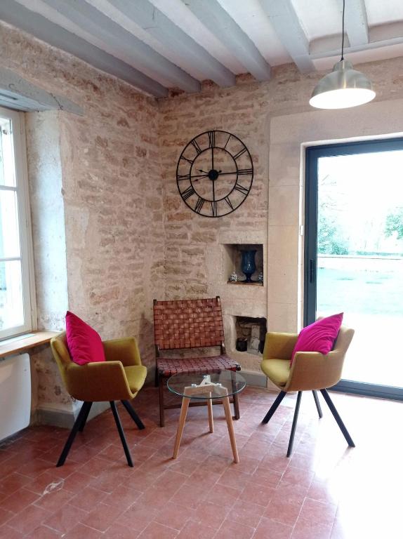 - un salon avec des chaises et une horloge murale dans l'établissement gite de séjour Vézelay La Romanella, à Asnières-sous-Bois