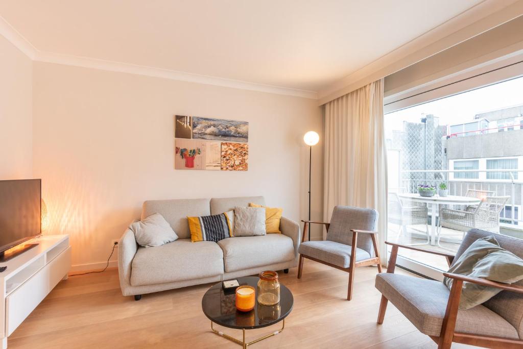 a living room with a couch and a table at Modern apartment with large terrace close to the sea in Ostend