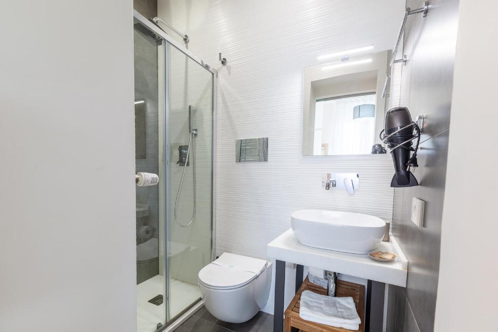 a bathroom with a toilet and a sink and a shower at Oneira Rooms in Agrigento