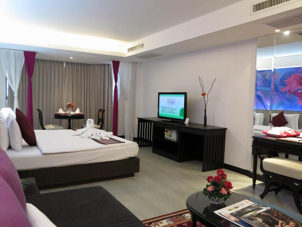 a hotel room with a bed and a flat screen tv at The Grand Sathorn in Bangkok