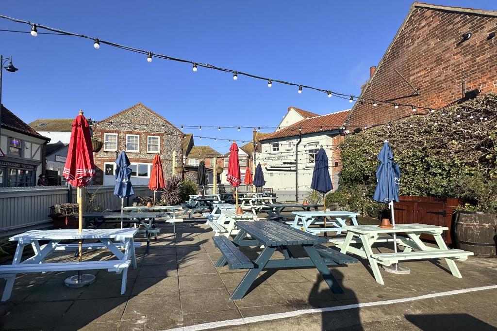 a group of picnic tables and umbrellas on a patio at The Lobster in Sheringham